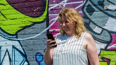Margaret met telefoon voor graffitimuur: ChatGPT voor tekstschrijvers ideaal